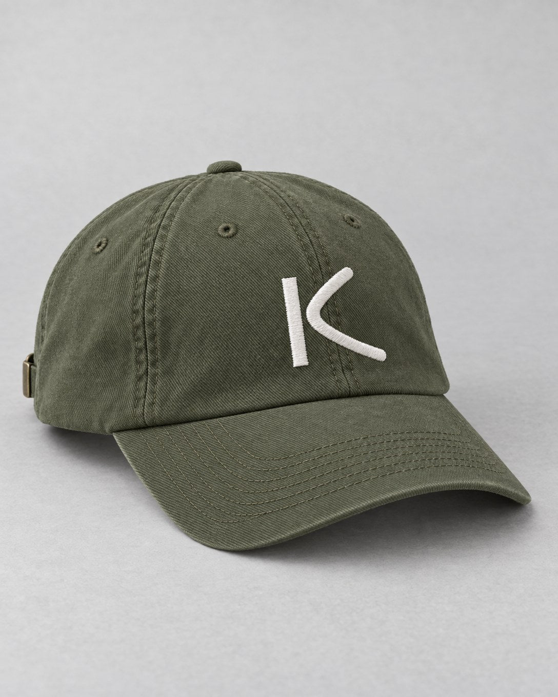 An olive six-panel cap with a chalk-white K stitched on the front.
