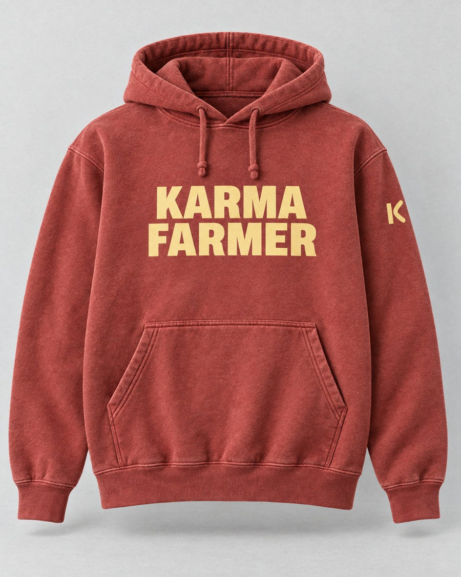 The sun-faded red Summer Hoodie from the front, with KARMA FARMER in pale yellow block capitals and a small K on the sleeve.