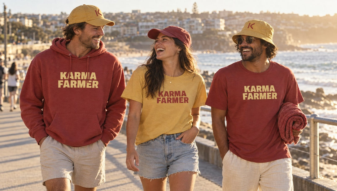 Three friends walk along a beach promenade in the Summer Hoodie, the mustard and red Summer Tees, K caps and a bucket hat.
