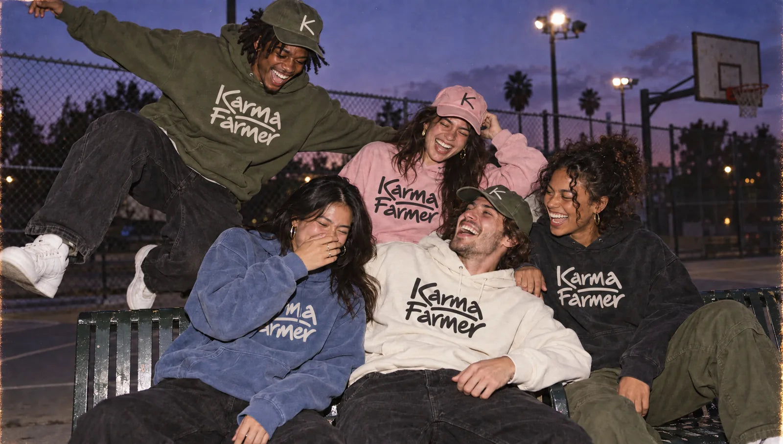 Five friends laughing on a basketball court bench at dusk in Karma Farmer tees, hoodies and K caps.